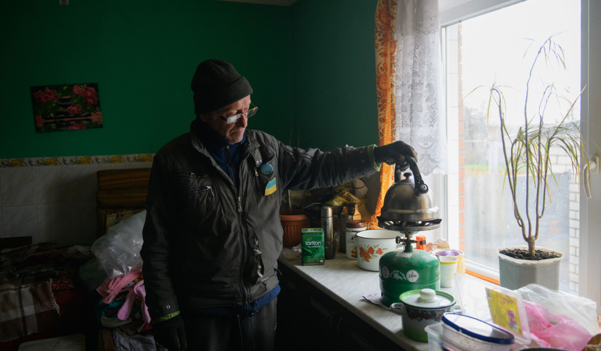 在烏克蘭的卡爾可夫地區，一名年長男子在沒電、沒瓦斯的情況下，用瓦斯罐燒水；2022年10月。© Amnesty International