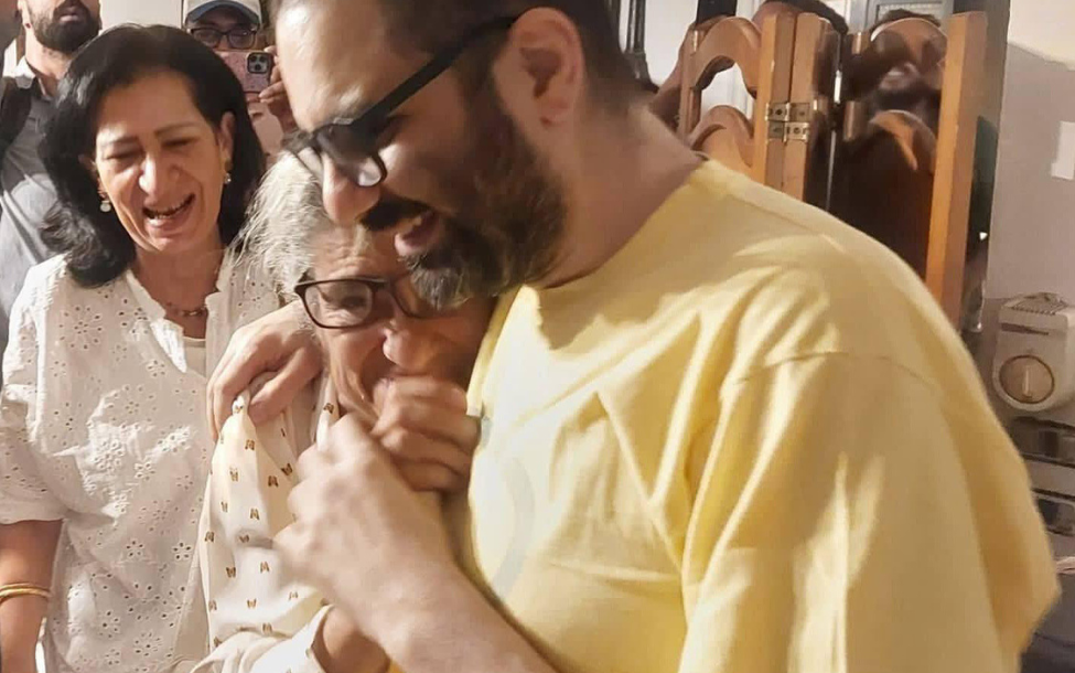 照片中，阿拉身穿黃色衣服，緊緊抱著年邁的母親，母親依偎在他的胸前。 